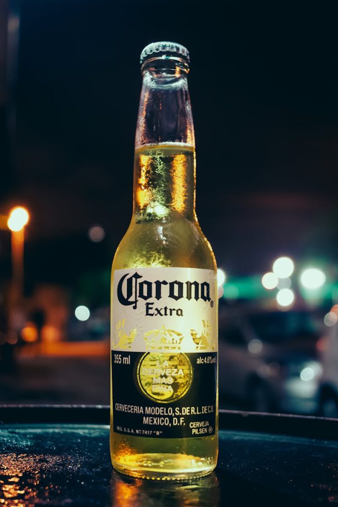 A bottle of Corona beer stands illuminated against a blurred night city background, creating a vibrant urban atmosphere.